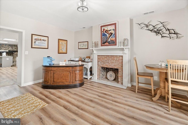 office with a brick fireplace and light hardwood / wood-style floors