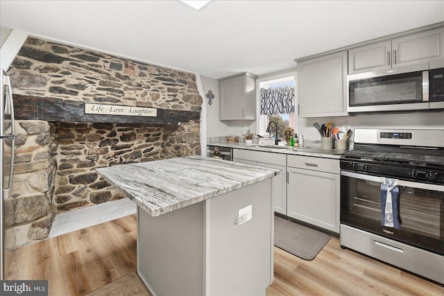 kitchen with stainless steel appliances, a center island, sink, and light hardwood / wood-style flooring