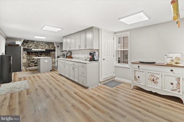 kitchen with stainless steel refrigerator, light hardwood / wood-style flooring, and gray cabinetry