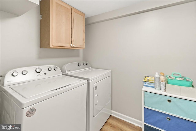 washroom with cabinets, washer and dryer, and light wood-type flooring