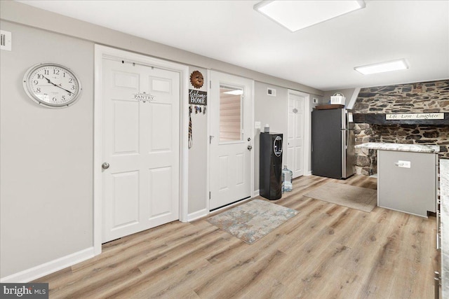 kitchen featuring white cabinetry, stainless steel refrigerator, and light hardwood / wood-style flooring