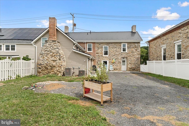 back of property featuring cooling unit and a lawn