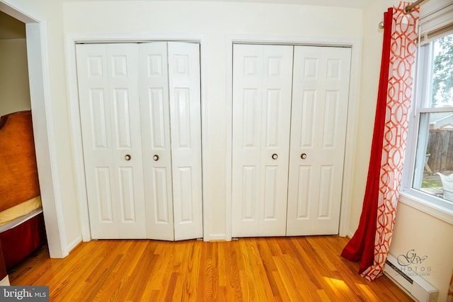 unfurnished bedroom featuring light hardwood / wood-style floors, multiple windows, and multiple closets