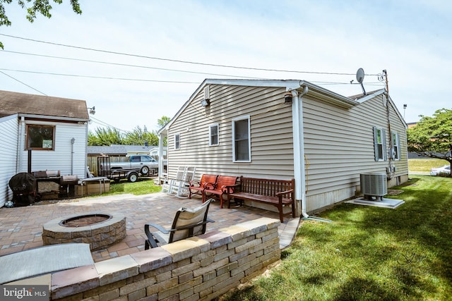 exterior space with central air condition unit, a patio area, a lawn, and an outdoor living space with a fire pit