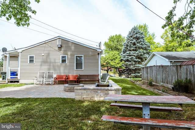 rear view of property featuring a yard, an outdoor fire pit, a patio area, and central air condition unit