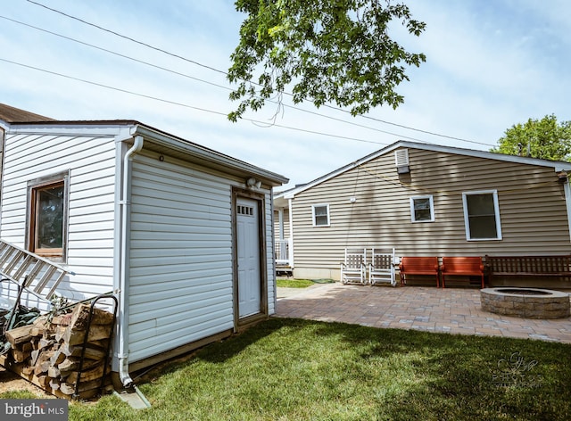 back of house with a patio area, a yard, and an outdoor fire pit