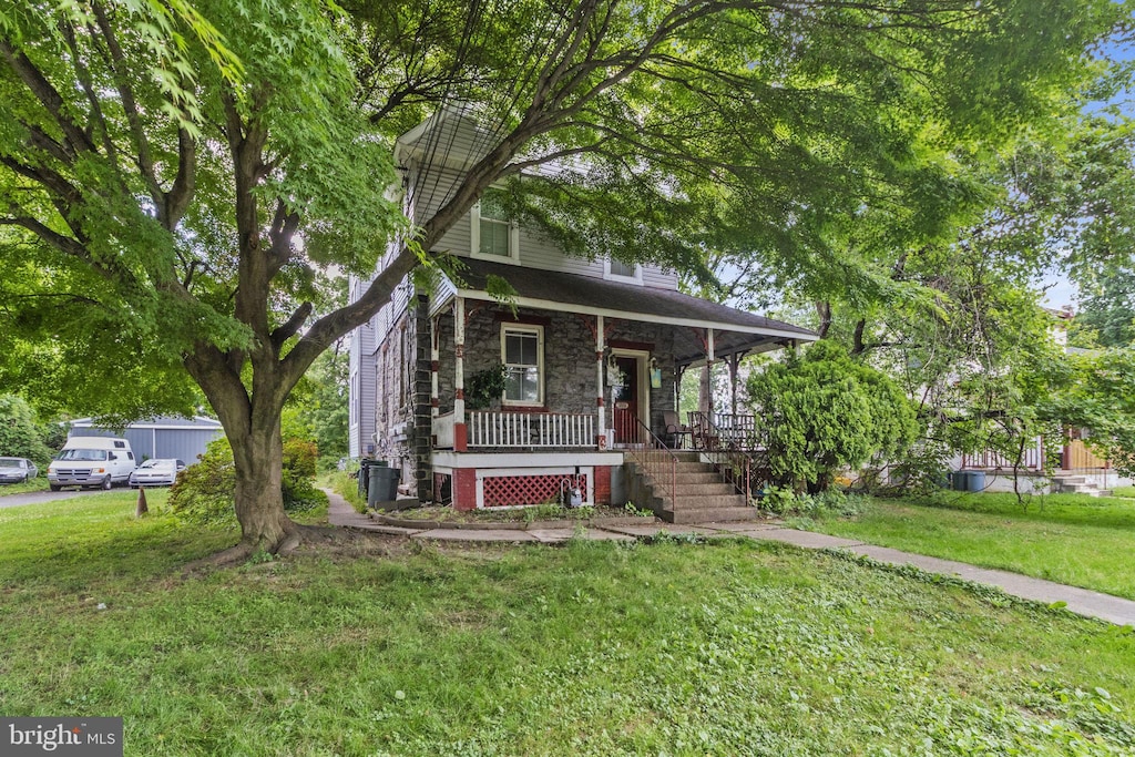 view of front of house featuring cooling unit, a front lawn, and a porch