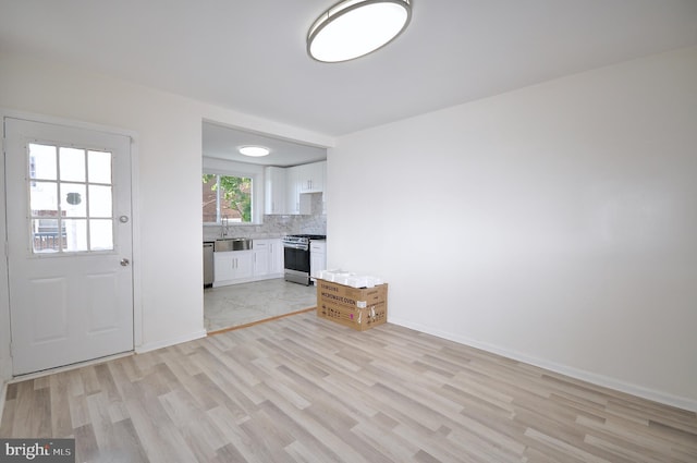 unfurnished living room featuring sink and light wood-type flooring