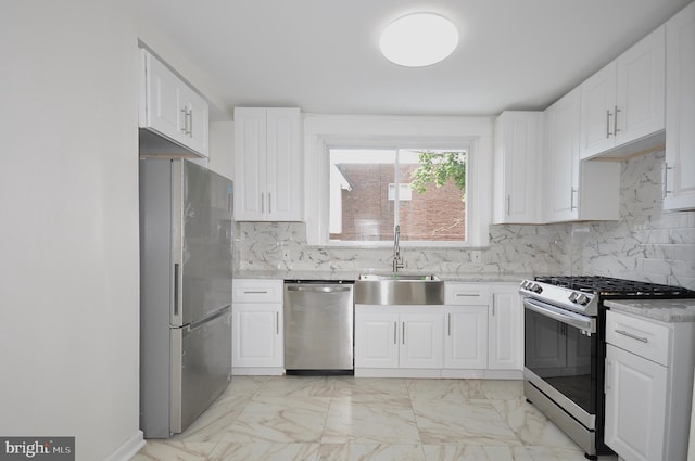 kitchen with white cabinets, appliances with stainless steel finishes, decorative backsplash, and sink