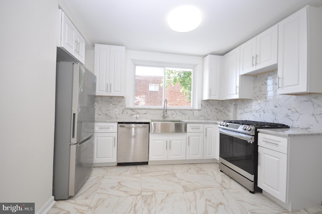 kitchen with white cabinets, decorative backsplash, stainless steel appliances, and sink