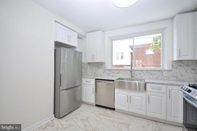 kitchen featuring light stone countertops, appliances with stainless steel finishes, white cabinetry, and sink