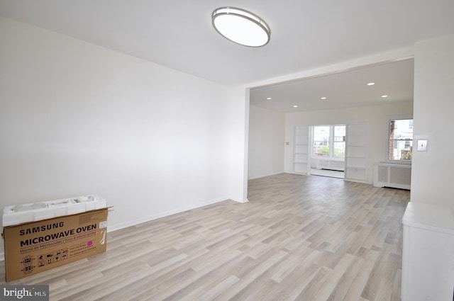 empty room with light wood-type flooring and radiator