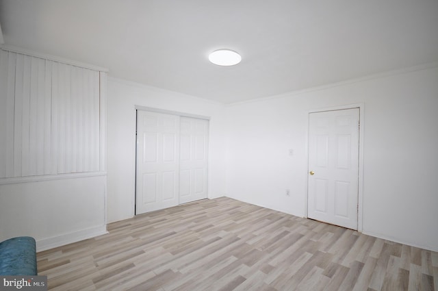 unfurnished bedroom with light hardwood / wood-style floors, a closet, and crown molding