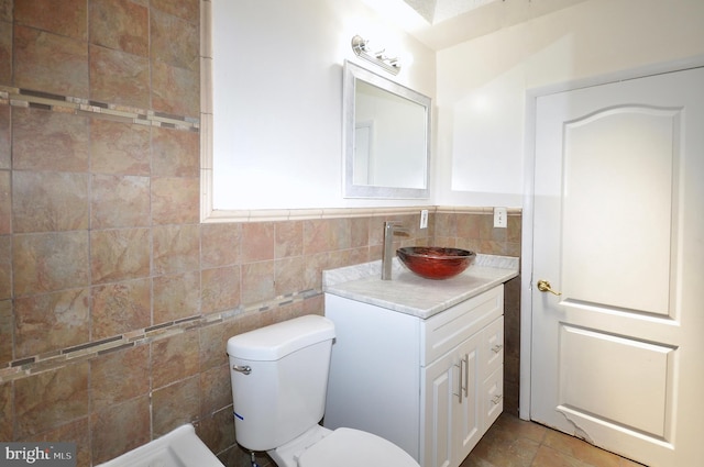 bathroom featuring tile patterned flooring, vanity, toilet, and tile walls