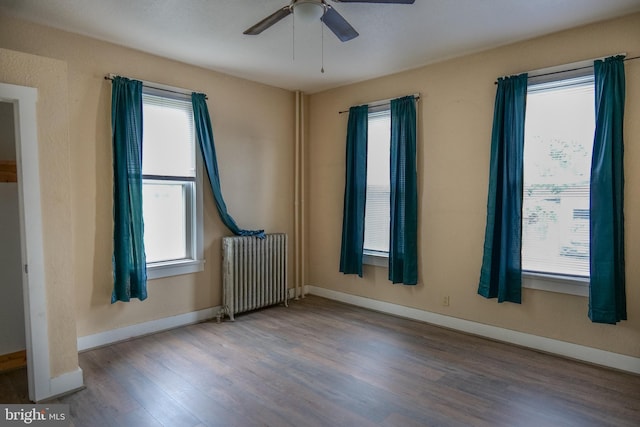 unfurnished room featuring hardwood / wood-style flooring, ceiling fan, and radiator heating unit