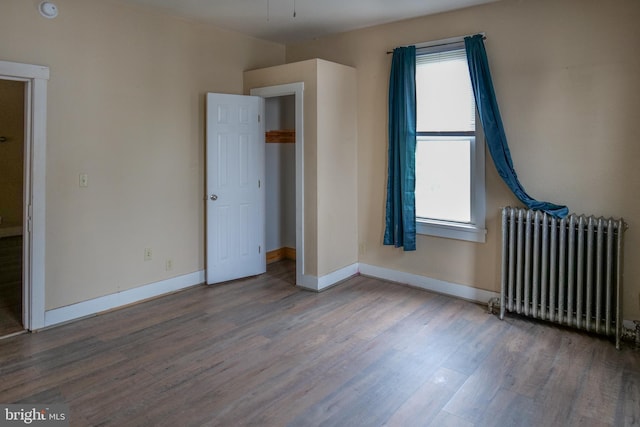 unfurnished bedroom featuring radiator heating unit and hardwood / wood-style floors