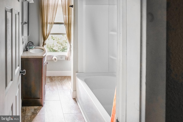 bathroom featuring tile patterned flooring, vanity, and a tub to relax in