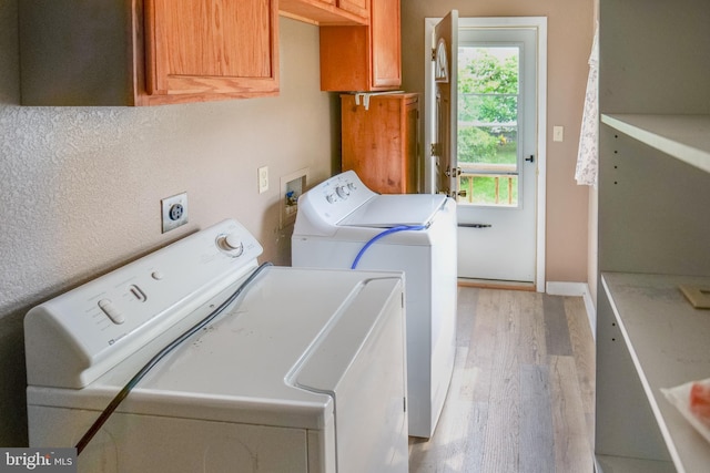 laundry room with washer and dryer, cabinets, and light wood-type flooring