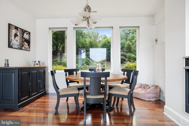 dining space with an inviting chandelier, a wealth of natural light, and dark wood-type flooring