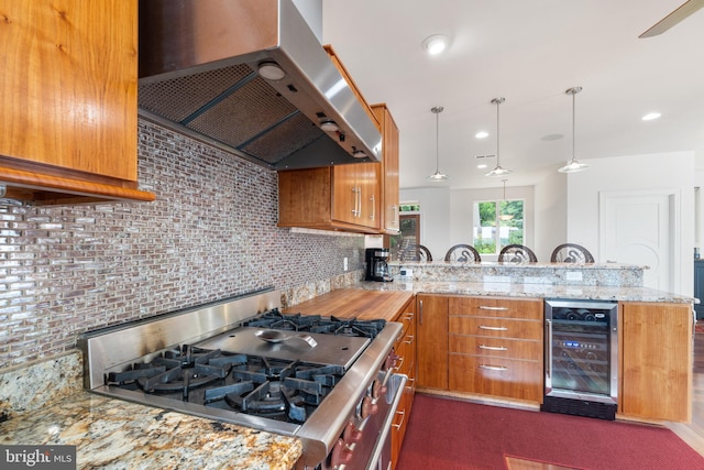 kitchen with kitchen peninsula, ventilation hood, pendant lighting, range, and wine cooler