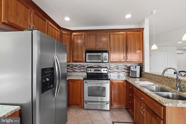 kitchen with sink, stainless steel appliances, light stone counters, backsplash, and decorative light fixtures