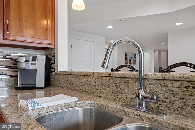 room details with backsplash, light stone counters, and sink