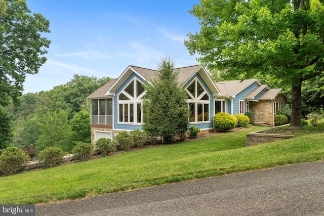 view of front facade featuring a front yard, a garage, and a sunroom