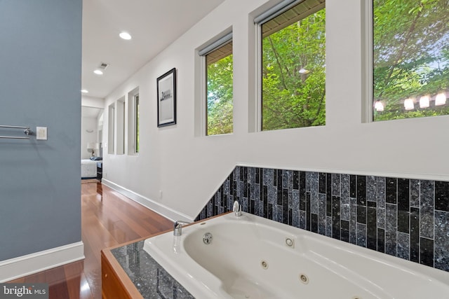 bathroom featuring hardwood / wood-style flooring and a relaxing tiled tub