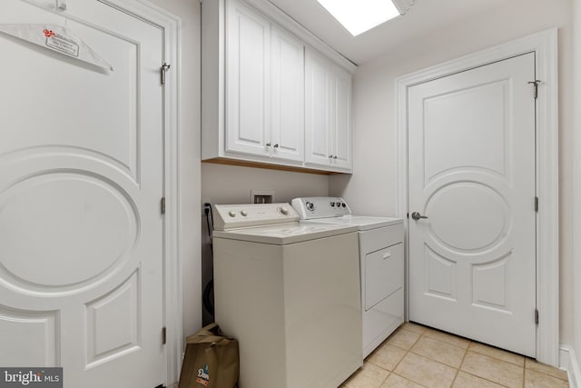 clothes washing area with cabinets, independent washer and dryer, and light tile patterned flooring