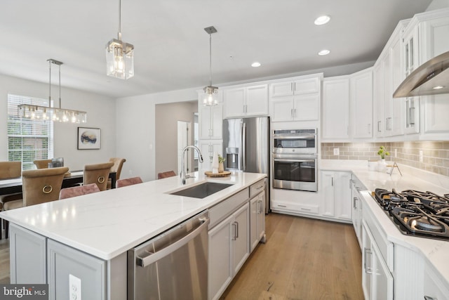 kitchen featuring pendant lighting, backsplash, a kitchen island with sink, sink, and stainless steel appliances