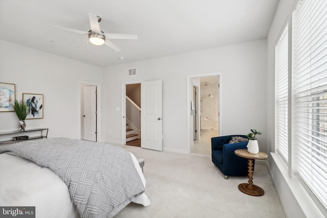 bedroom featuring light colored carpet, ensuite bath, and ceiling fan