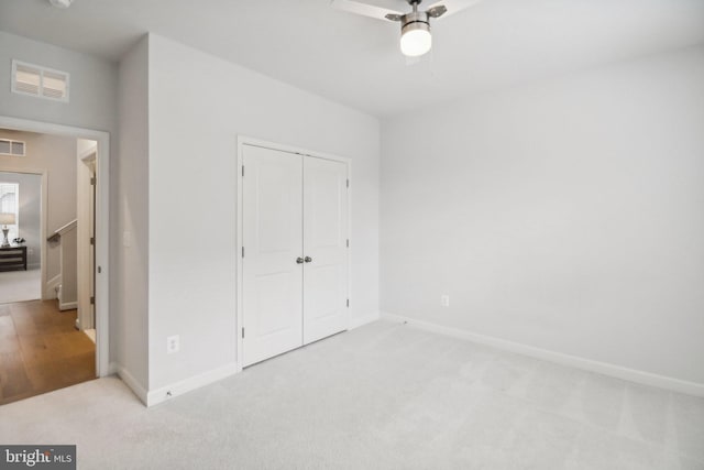 unfurnished bedroom featuring light carpet, a closet, and ceiling fan