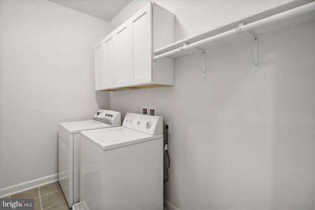 clothes washing area with light tile patterned flooring, cabinets, and washing machine and dryer