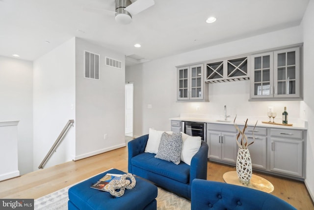 living room featuring light hardwood / wood-style floors, wine cooler, ceiling fan, and sink