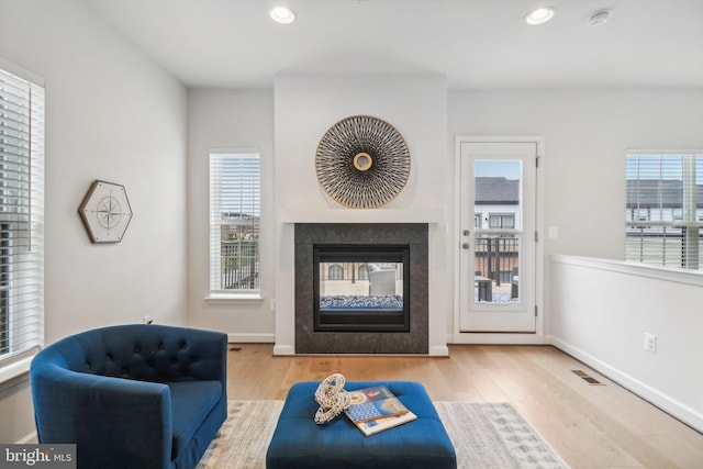 living room featuring a multi sided fireplace and light hardwood / wood-style flooring