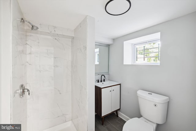 bathroom with a tile shower, vanity, and toilet