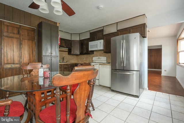 kitchen featuring a sink, white appliances, dark brown cabinetry, light tile patterned floors, and ceiling fan