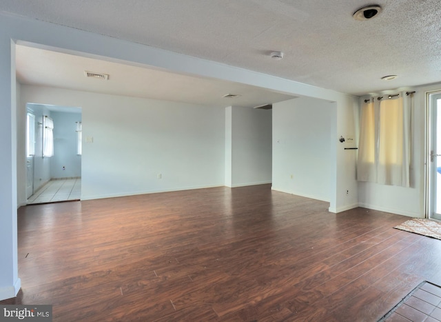 spare room with plenty of natural light, wood finished floors, visible vents, and a textured ceiling