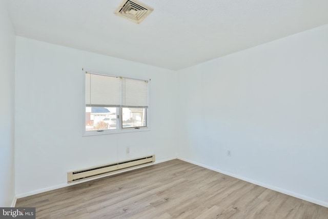 spare room featuring baseboards, wood finished floors, visible vents, and a baseboard radiator