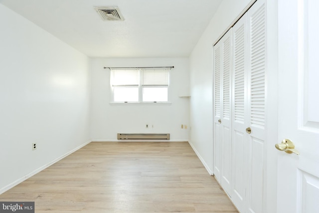 unfurnished bedroom with visible vents, baseboards, baseboard heating, light wood-style floors, and a closet