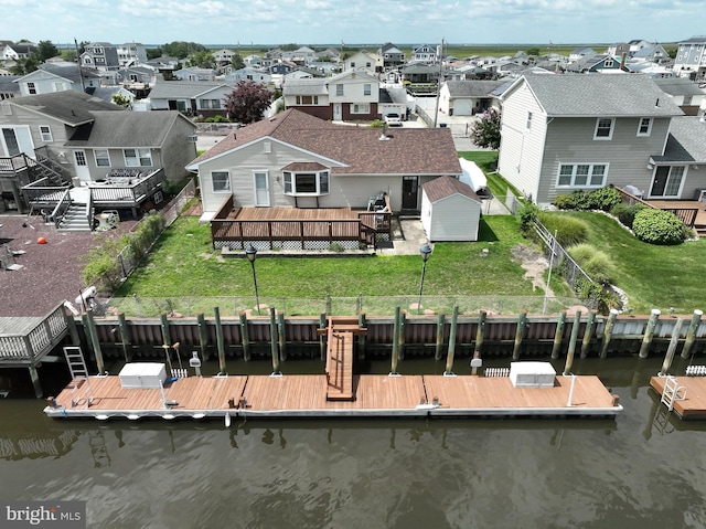 exterior space featuring a water view, a residential view, a lawn, an outdoor structure, and a fenced backyard