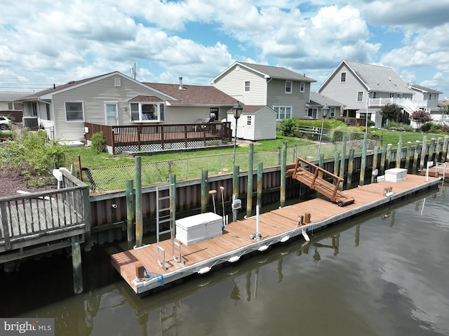 dock area featuring fence, a lawn, a residential view, and a water view