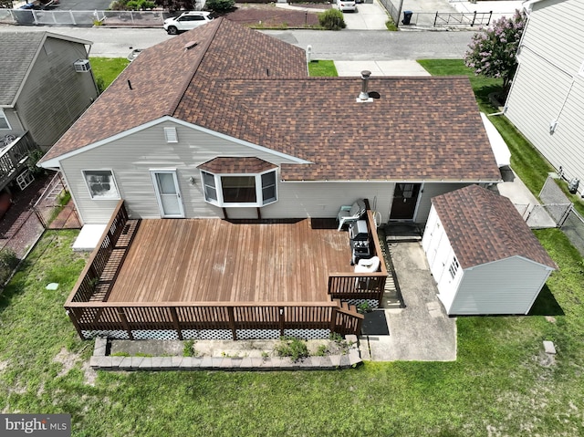 back of house featuring a shingled roof, a yard, and a wooden deck