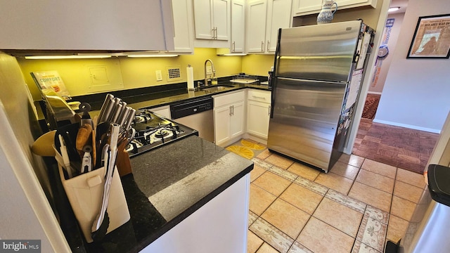 kitchen with appliances with stainless steel finishes, light tile patterned floors, white cabinetry, and sink