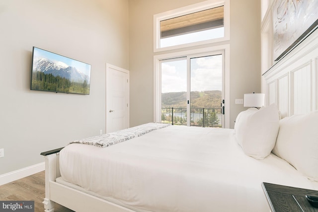 bedroom with a high ceiling, access to outside, and light hardwood / wood-style flooring