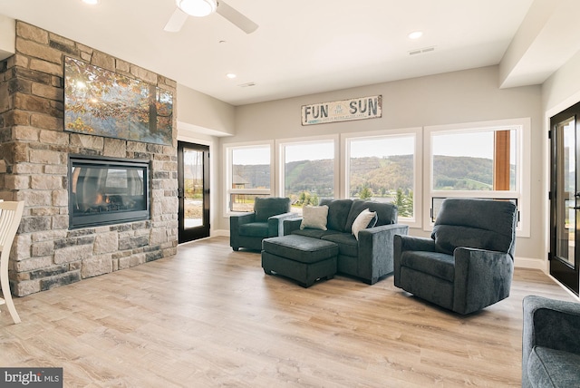 living room featuring a mountain view, a fireplace, a wealth of natural light, and light hardwood / wood-style flooring