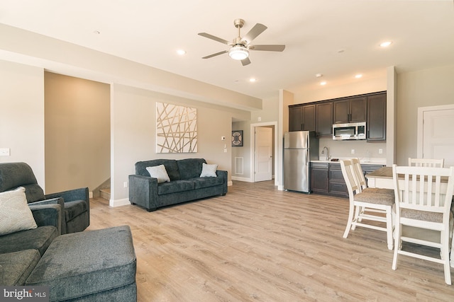 living room featuring light hardwood / wood-style floors, ceiling fan, and sink