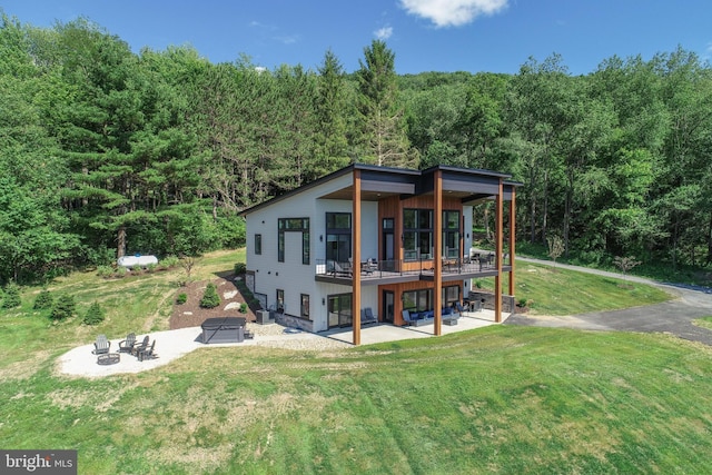 rear view of property with a yard, a patio, a deck, and an outdoor fire pit