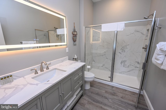 bathroom with toilet, vanity, a shower with door, and hardwood / wood-style flooring