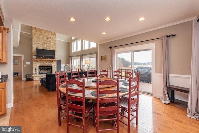 dining space with a textured ceiling, light hardwood / wood-style floors, crown molding, and a fireplace